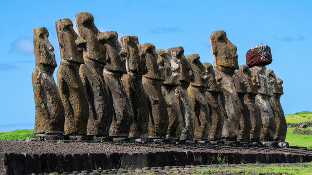 Moai statues stand in a row at Ahu Tongariki on Easter Island in Chile under a clear blue sky