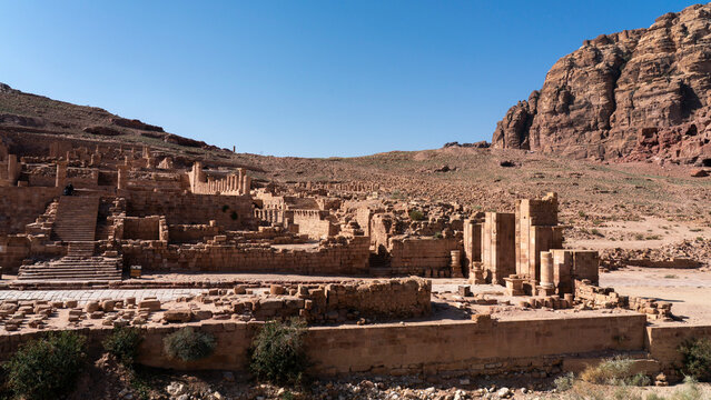 Exploring the ruins of the Great Temple in Petra, Jordan with ancient stone structures under a clear blue sky