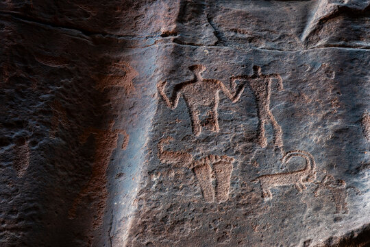 Ancient stone-age petroglyphs show human figures and animals in desert canyon site of Khazali Canyon in Jordan