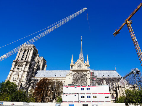 Restoration work in progress at Notre Dame Cathedral with cranes and scaffolding in Paris during clear weather