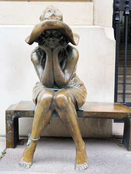 Sitting figure in bronze hat resting on a bench outside the Institut Liszt in Paris, Ile de France, France