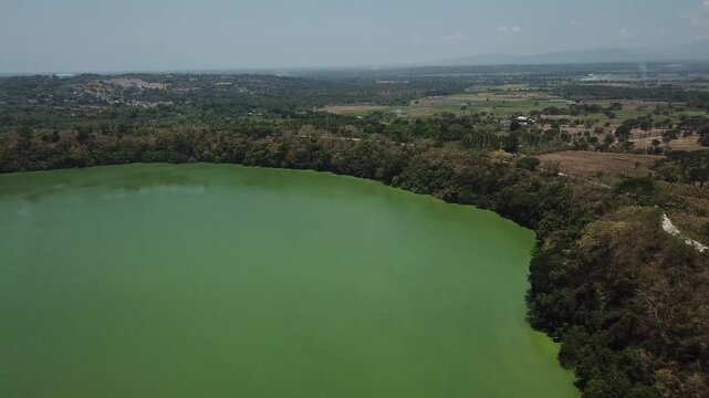 stunning aerial view of a secluded lake, surrounded by a dense forest filled with green algae, remains inaccessible to the locals of Lake Tikub in Tiaong, Quezon, Philippines