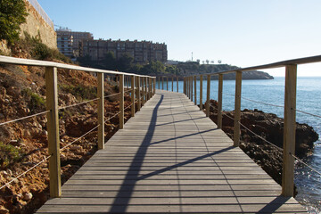 Naklejka premium Wooden boardwalk along the coast with buildings and the sea