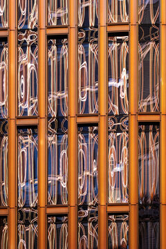 Vertical metal lines and reflection fill windows on an abstract architecture facade where pattern and building detail create a layered exterior rhythm