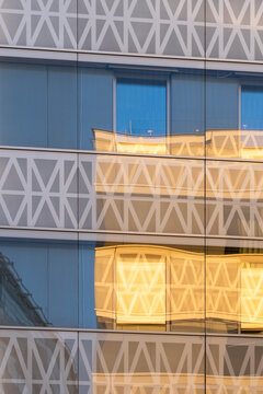 Warm light reflection moves across glass windows on an abstract architecture facade where geometric pattern and exterior detail shape a clean building study