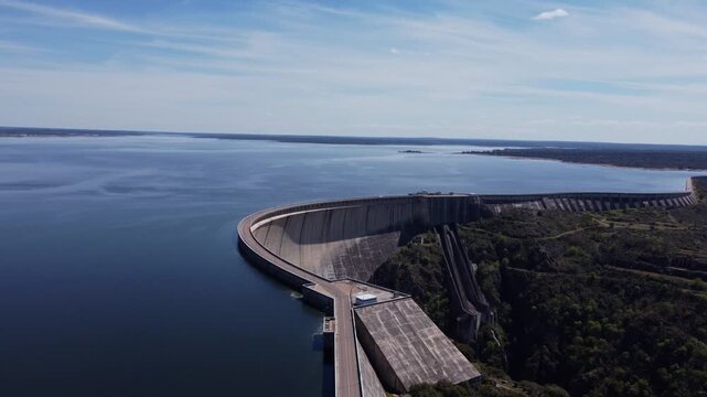 4K drone rotation over the Almendra Dam in Salamanca, Spain. This massive concave concrete structure holds back Spain's largest reservoir under a clear sunny sky