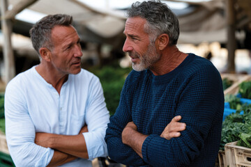Fototapeta premium Two Men Engaged in Serious Conversation at Market, Reflective Social Interaction, Community Engagement and Personal Relationships, Bustling Outdoor Marketplace Atmosphere Scene