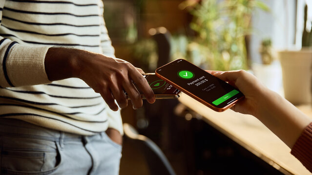 Contactless payment between two smartphones with confirmation screen in modern interior. Concept of peer to peer transfer, cashless checkout, mobile wallet and fintech service.