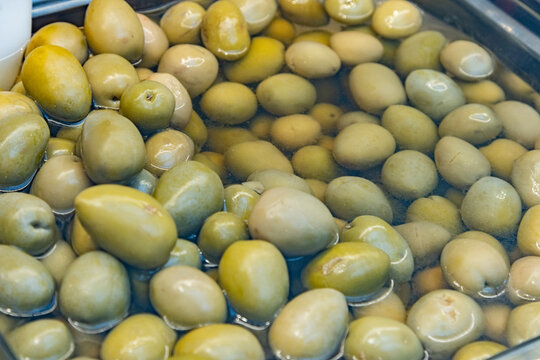 Close up of fresh green olives in brine for sale at a market