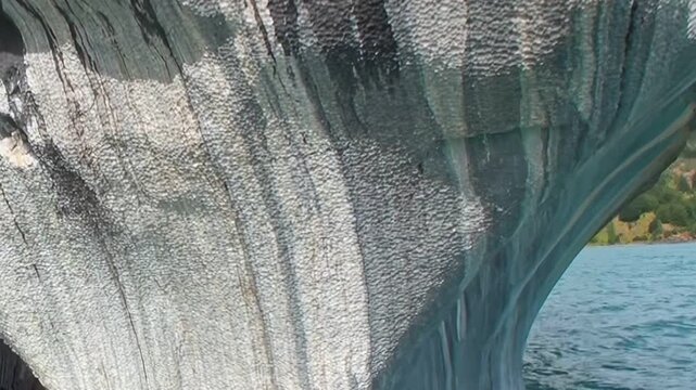 Glimpse breathtaking beauty of Marble Caves in Patagonia. Intricate patterns of blue and grey stone shimmer under gentle light, revealing nature's artistry. Water reflections dance ancient grottoes.