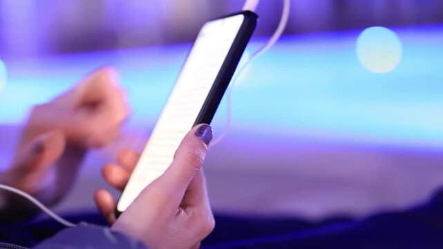 Woman using smartphone by pool at night &ndash; glowing screen, copy space, modern lifestyle.