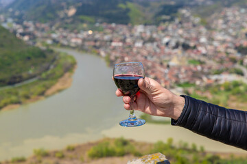 Obraz premium Georgian man in a papakhi with a glass of wine. Selective focus.