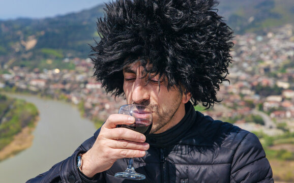 Georgian man in a papakhi with a glass of wine. Selective focus.