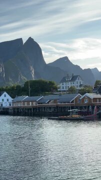 Bright yellow traditional rorbu houses in the fishing village of Sakrisoy with dramatic mountains, Lofoten Islands, Norway