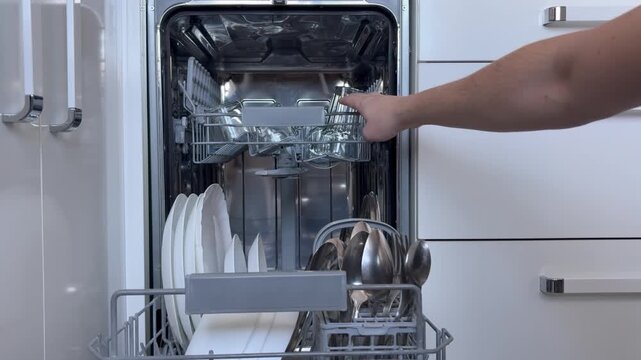 Men's hands open the dishwasher after a wash cycle and check the cleanliness of the dishes. Household appliances, everyday routine