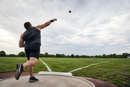 Track and Field Competitor Performing Shot Put Throw on Stadium Grass Field