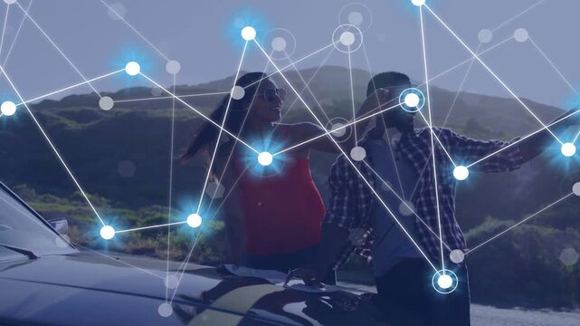 Couple leaning on car hood pointing, network overlay appearing across people showing links, tech