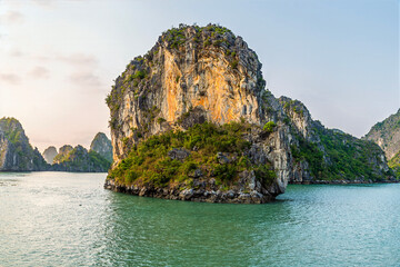Naklejka premium A view from a cruise ship into a lagoon past a Karst limestone islets in Ha Long Bay, Vietnam illuminated by the evening light