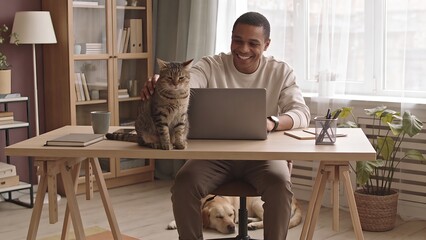 Plakat Happy Man Working on Laptop at Home Office While Petting His Cat with Dog Sleeping under Desk