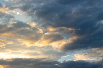 Obraz premium Dramatic Sunset Sky with Golden Sunbeams and Dark Storm Clouds