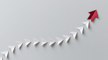 Minimal leadership concept with red paper arrow leading white arrows upward on clean gray background business growth success strategy and direction copy space