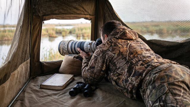Male Wildlife Photographer with Telephoto Lens Inside Portable Hide Overlooking Bird Wetland in Danube Delta, Wildlife Photography, Conservation, Outdoor Career, Birding
