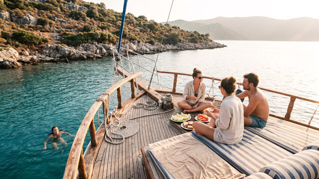 Friends Relaxing on Wooden Gulet Anchored at Rocky Cove on Turkish Aegean Coast with Swimmer in Turquoise Water, Travel, Friendship, Mediterranean Lifestyle, Sailing