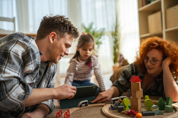 Family playing with building blocks and toy train at home