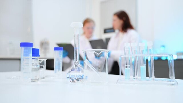 Two female researchers in lab coats and gloves operating medical equipment, analyzing samples, and taking notes during a scientific experiment
