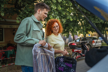 Naklejka premium Couple packing clothing and luggage into car trunk for travel