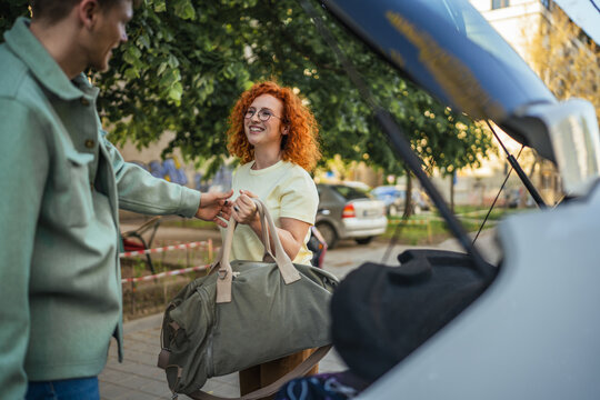 Young couple loading luggage into car trunk for road trip