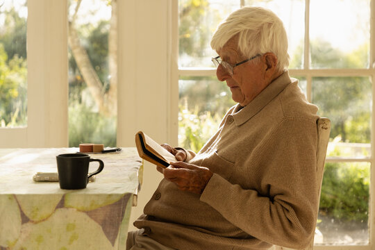 elderly man at home , reading a book