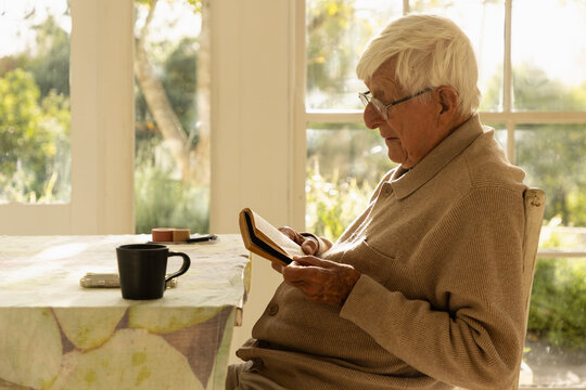 elderly man at home , reading a book