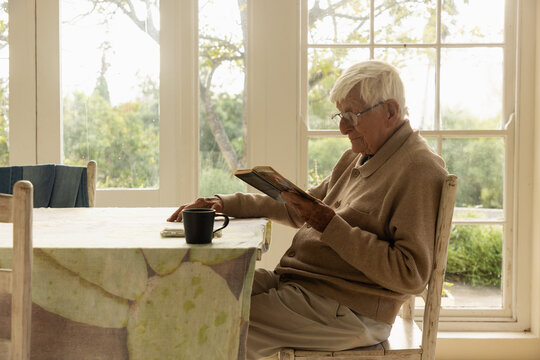 elderly man at table reading a book