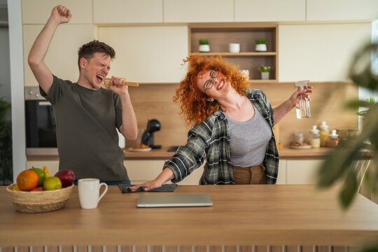 Happy couple dancing and cleaning kitchen together