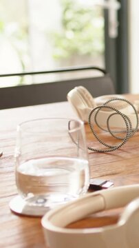 Vertical video: Panning camera bringing clear glass toward center on table, showing headphones USB