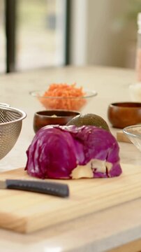 Vertical video: Pulling back camera showing cut purple cabbage on kitchen board with knife