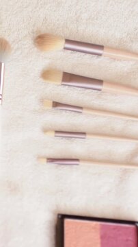 Vertical video: Panning camera showing brushes on towel, revealing palettes, blush, false lashes
