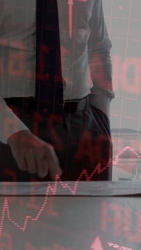 Vertical video: Engineer tracing, unrolling plans as peer pointing, red chart overlay assessing ROI