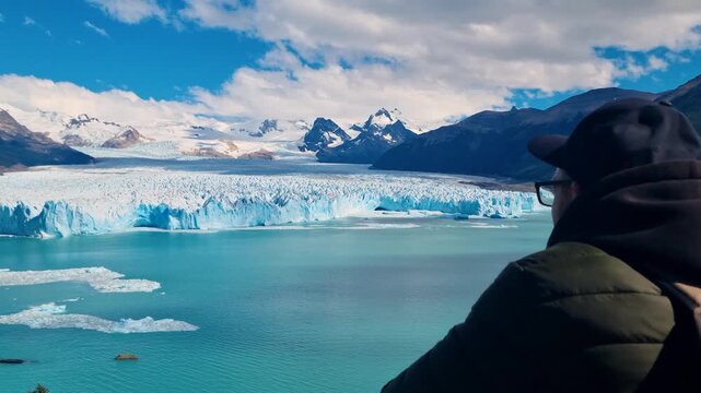 Filmed from behind, a man looks out over the Perito Moreno Glacier in PataA man is looking at a Perito Moreno glaciar in Patagonia, Argenina, filmed from behind, tourist spot and unesco world heritage