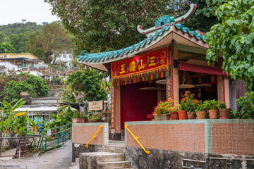 Obraz premium Lamma Island, Hong Kong, China: traditional Chinese village temple surrounded by tropical vegetation and rural houses near Ko Long Village on the island of Lamma. 