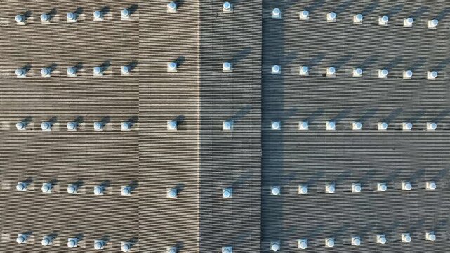 High-angle aerial shot of factory rooftop ventilators, emphasizing improved airflow management, reduced heat buildup, worker comfort, and modern industrial environmental control systems. 4k.
