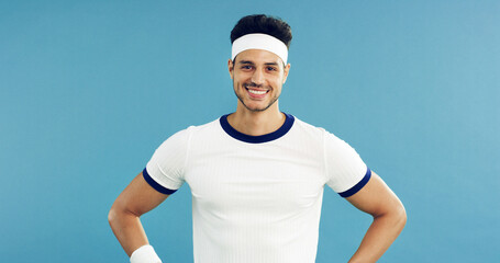 Fototapeta premium Portrait, smile and tennis with man on studio space for health, retro sports or wellness. Confidence, fitness and proud with happy person on blue background for competition, game or hobby as player