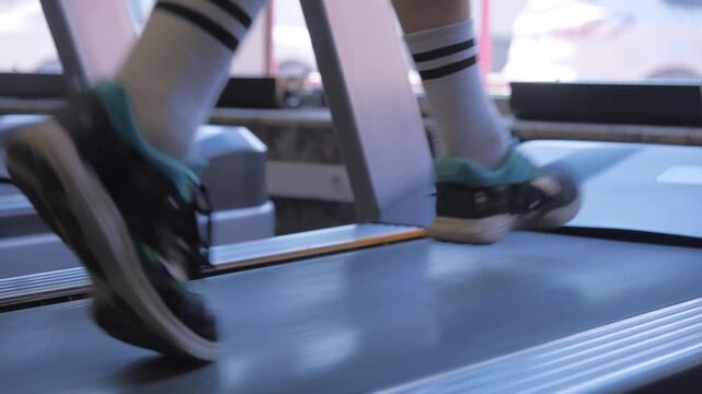 Running on treadmill in gym with focus on feet and shoes in bright indoor space for exercise motivation