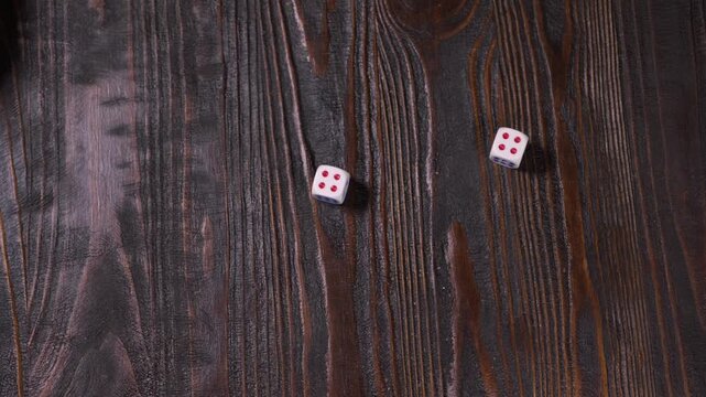 Hand rolls dice on wooden table in game setting with friends