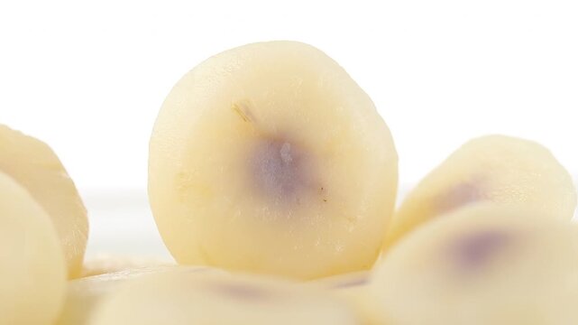Slowly rotating boiled and peeled water chestnuts arranged on a white background, Close-up view 