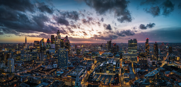 Panoramic aerial view of the illuminated London skyline from Spitalfields down to the Thames River during evening time