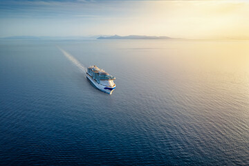 Naklejka premium High aerial view of a cruise ship sailing over blue ocean into the sunset with copy space as a concept for travel and vacation