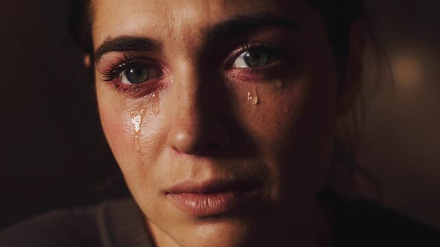 Close up portrait of a young woman crying with tears streaming down her face showing deep emotion and sadness