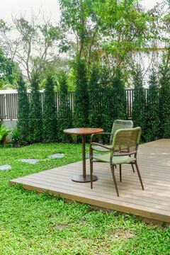 Wooden table and chair set in garden on a sunny day,outdoor seating for restaurant or cafe,Neat paved patio with sitting area and small garden in forest.